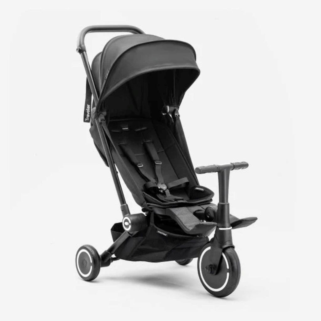 Vista en ángulo del coche triciclo evolutivo SmarTrike Traveler en negro, con toldo solar amplio, asiento con arnés de 5 puntos, barra delantera, canasta de almacenamiento inferior y tres ruedas con aros blancos. Fondo blanco.