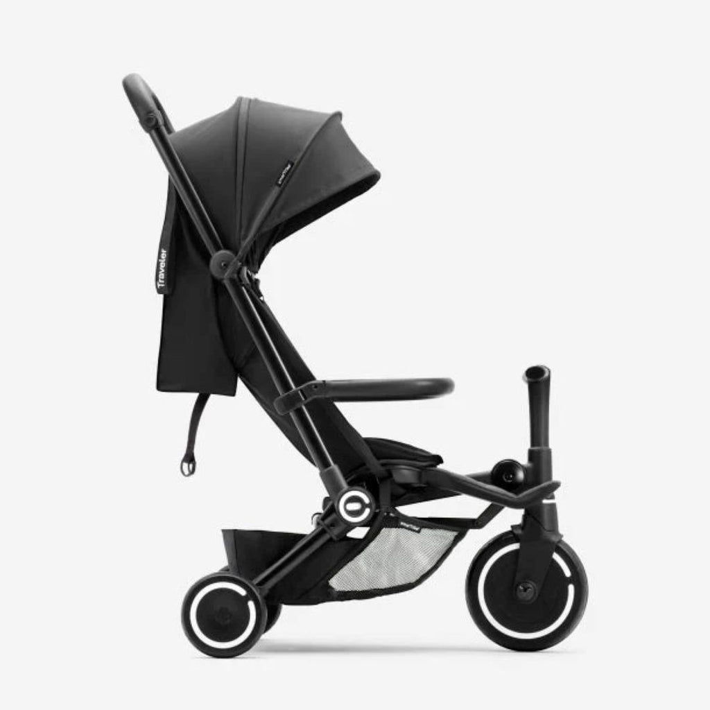 Vista lateral del coche triciclo SmarTrike Traveler negro en modo paseo con toldo desplegado, respaldo vertical y canasta inferior, sobre fondo gris claro.