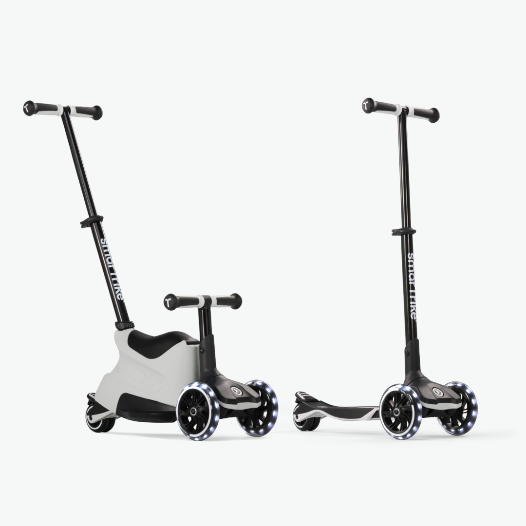 Dos vistas del scooter evolutivo SmarTrike Xtend Ride-On Gris: a la izquierda en modo ride-on con asiento y barra para padres, y a la derecha en modo scooter autónomo con manubrio vertical y ruedas LED. Fondo gris muy claro.