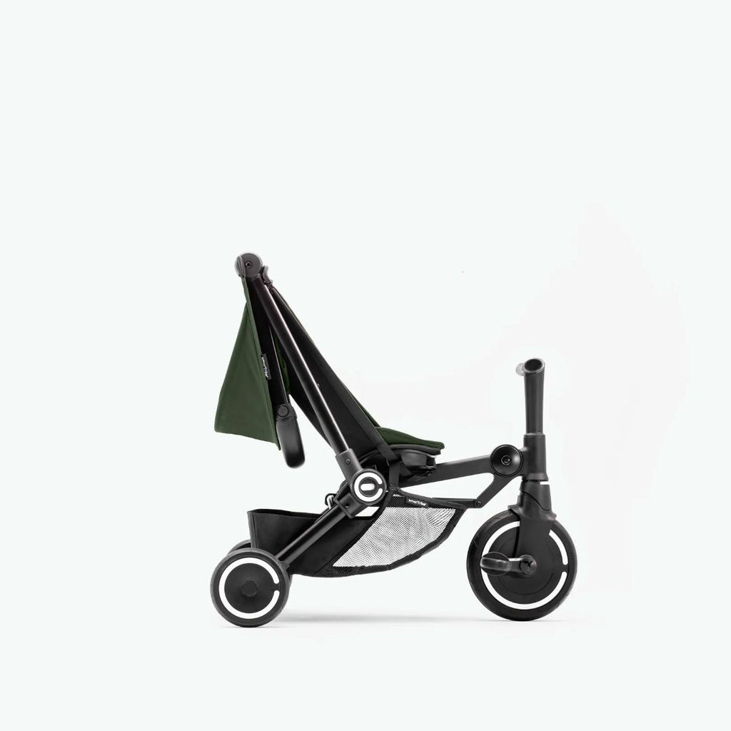Coche triciclo SmarTrike Traveler verde en modo triciclo, y con respaldo reclinado. Fondo verde muy claro.