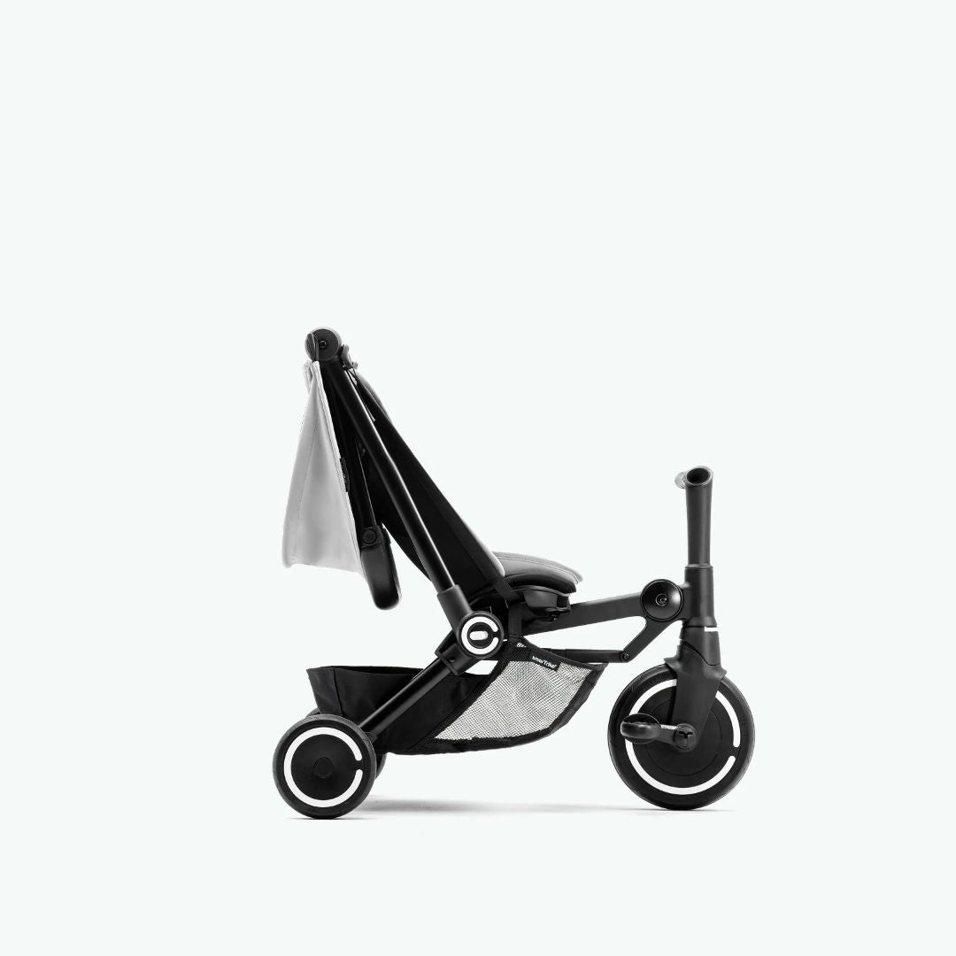 Coche triciclo SmarTrike Traveler gris claro en modo triciclo, y con respaldo reclinado. Fondo gris claro.