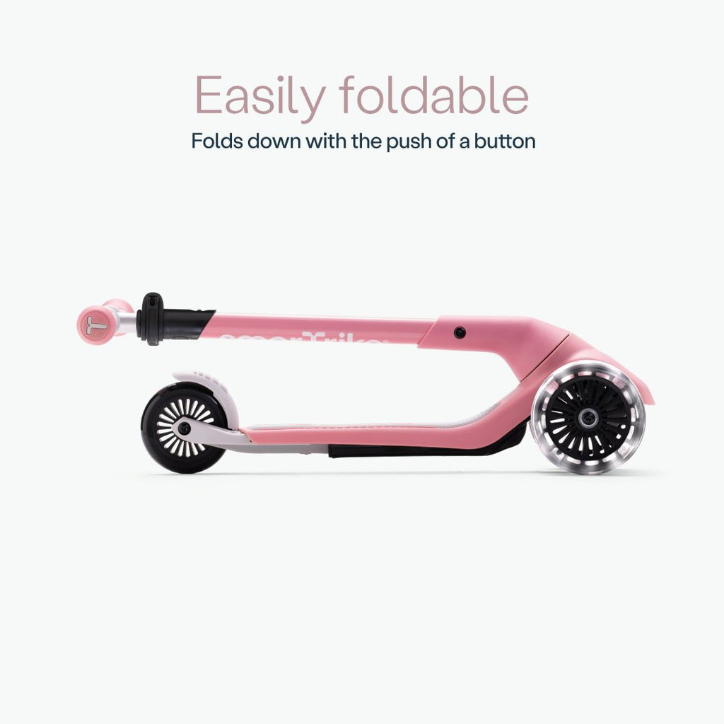 Vista lateral del scooter SmarTrike Xtend Mini+ color Palo Rosa completamente plegado en formato compacto, con ruedas LED visibles. Texto: "Easily foldable. Folds down with the push of a button." Fondo gris muy claro.
