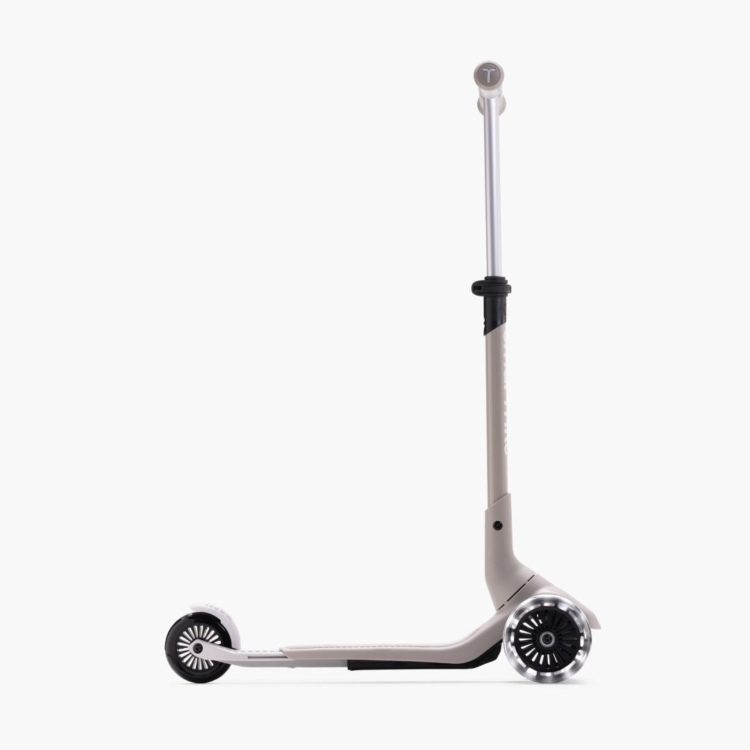 Vista lateral del scooter SmarTrike Xtend Mini+ Gris en modo scooter con manubrio y plataforma extendidos al máximo y ruedas LED. Fondo blanco.