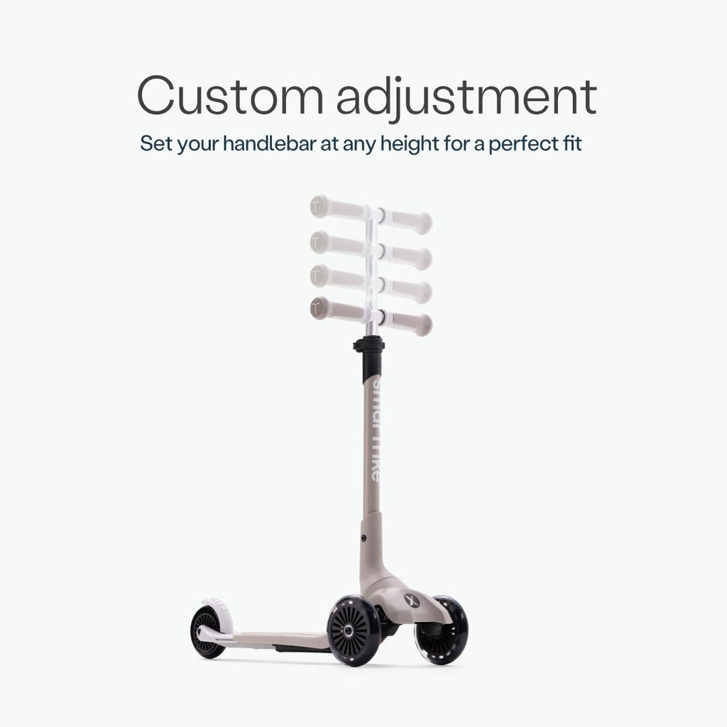 Infografía del scooter SmarTrike Xtend Mini+ Gris mostrando las 5 posiciones de altura del manubrio ajustable, ilustradas con superposición de imágenes translúcidas. Texto: "Custom adjustment. Set your handlebar at any height for a perfect fit." Fondo gris muy claro.