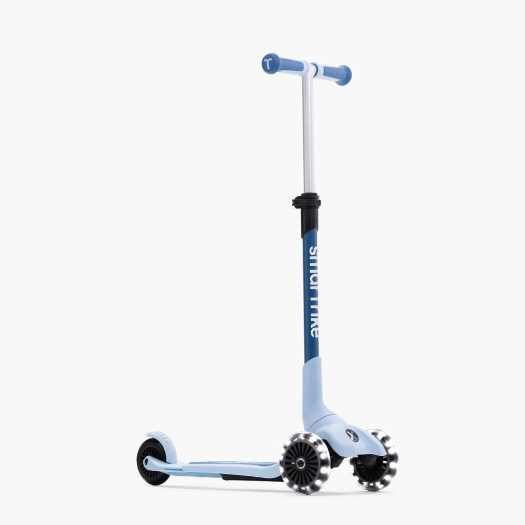 Vista lateral del scooter evolutivo SmarTrike Xtend Mini+ en color Celeste con manubrio en T azul oscuro, cuerpo celeste, estructura blanca y tres ruedas con luz LED. Fondo blanco.