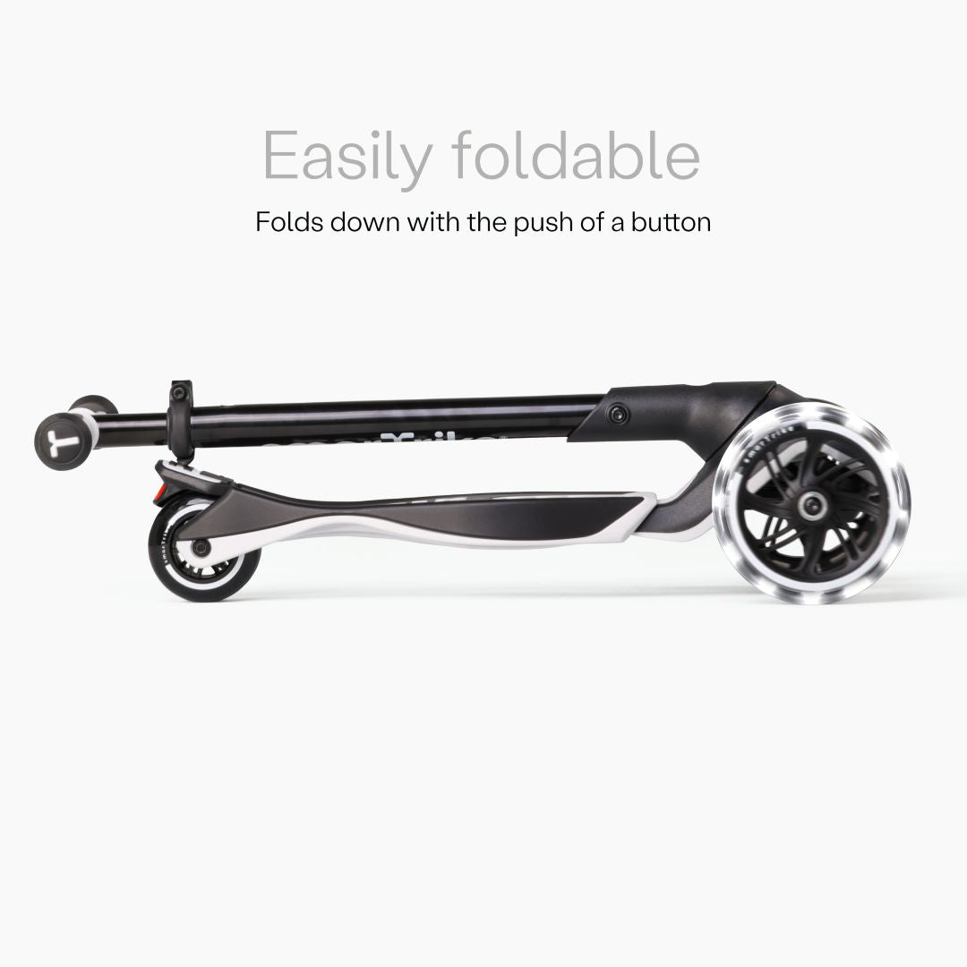 Vista lateral del scooter SmarTrike Xtend Ride-On Gris completamente plegado en formato compacto, con ruedas LED visibles. Texto: "Easily foldable. Folds down with the push of a button." Fondo gris claro.