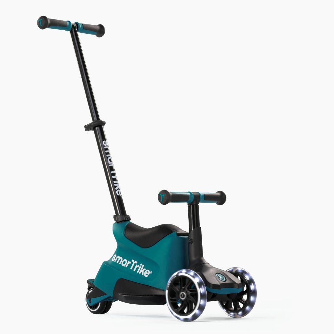 Vista frontal en ángulo del scooter evolutivo SmarTrike Xtend Ride-On Petróleo en modo ride-on, con asiento, manubrio para niño, barra para padres inclinada y tres ruedas con luz LED. Fondo blanco.