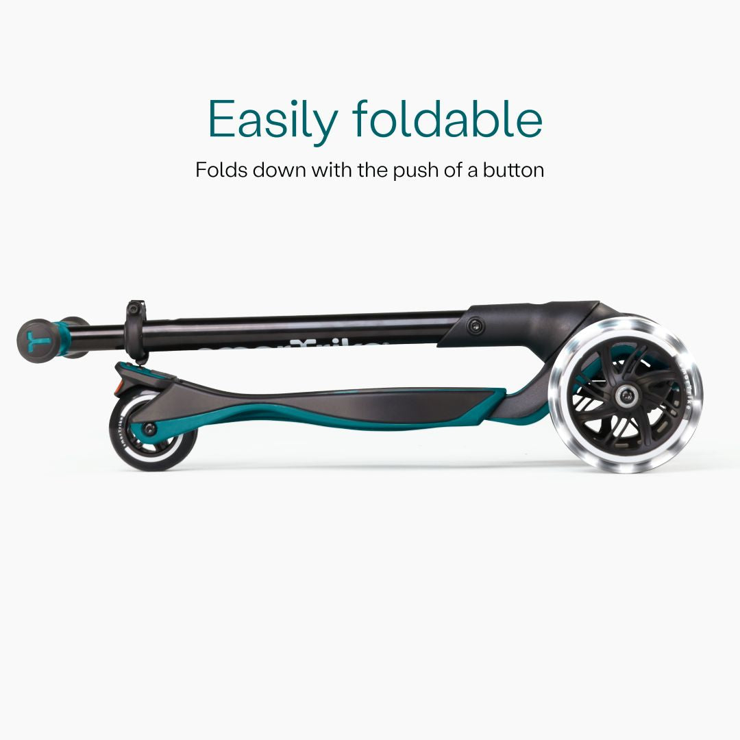 Vista lateral del scooter SmarTrike Xtend Ride-On Petróleo completamente plegado en formato compacto, con ruedas LED visibles. Texto: "Easily foldable. Folds down with the push of a button." Fondo gris claro.