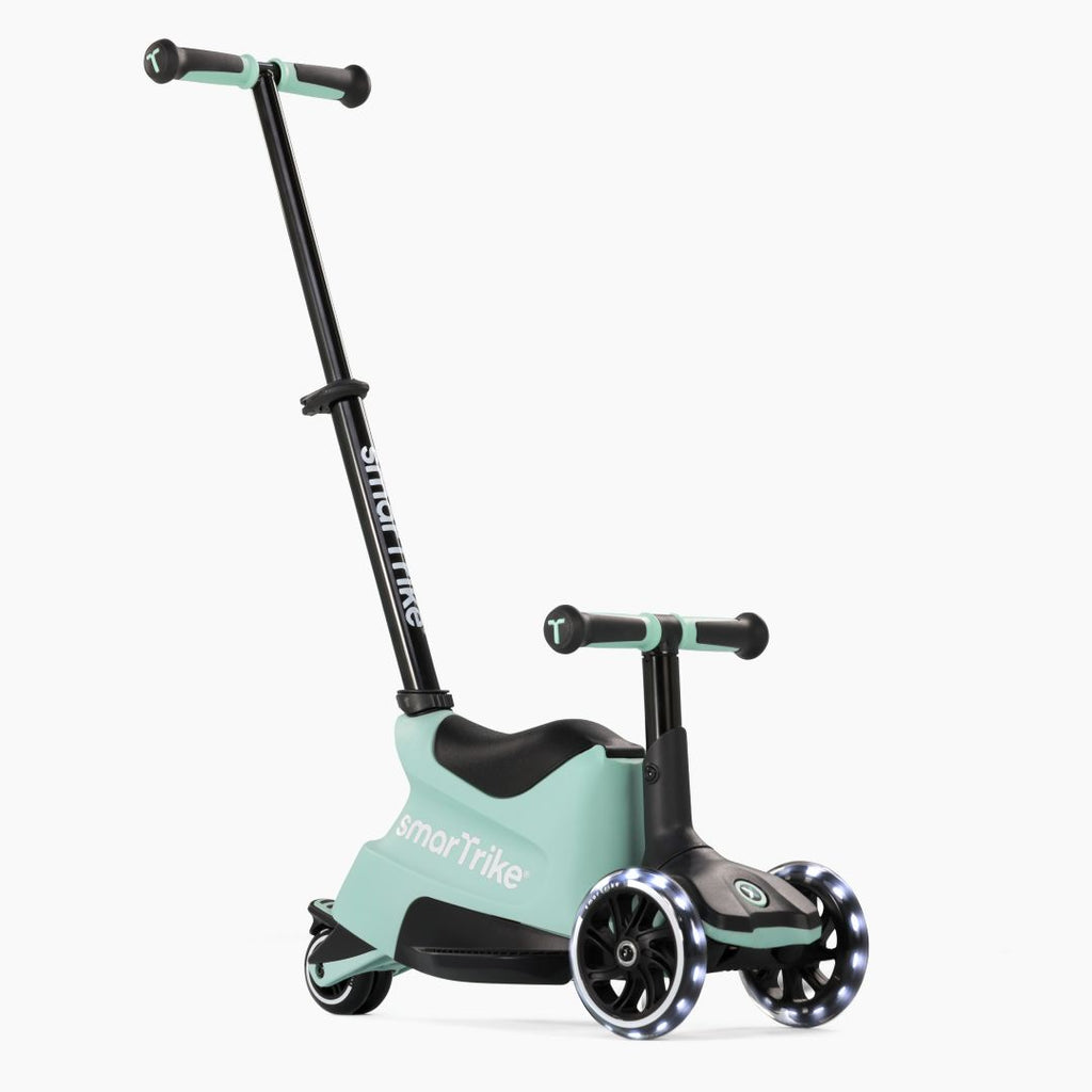 Vista frontal en ángulo del scooter evolutivo SmarTrike Xtend Ride-On Verde Agua en modo ride-on, con asiento, manubrio para niño, barra para padres inclinada y tres ruedas con luz LED. Fondo blanco.