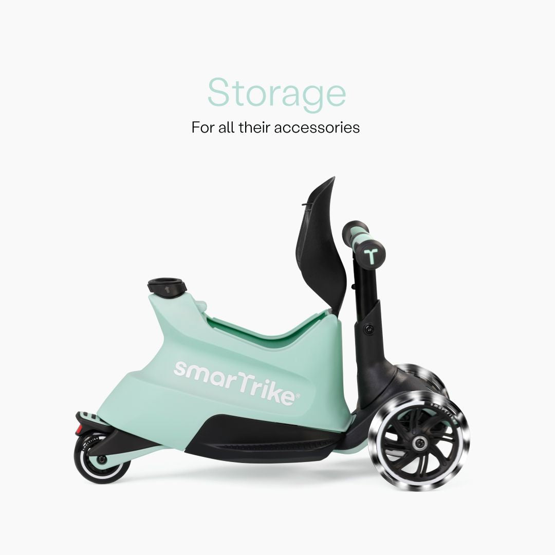 Vista lateral del scooter SmarTrike Xtend Ride-On Verde Agua en modo ride-on mostrando el compartimento de almacenamiento abierto bajo el asiento y ruedas LED. Texto: "Storage. For all their accessories." Fondo blanco.