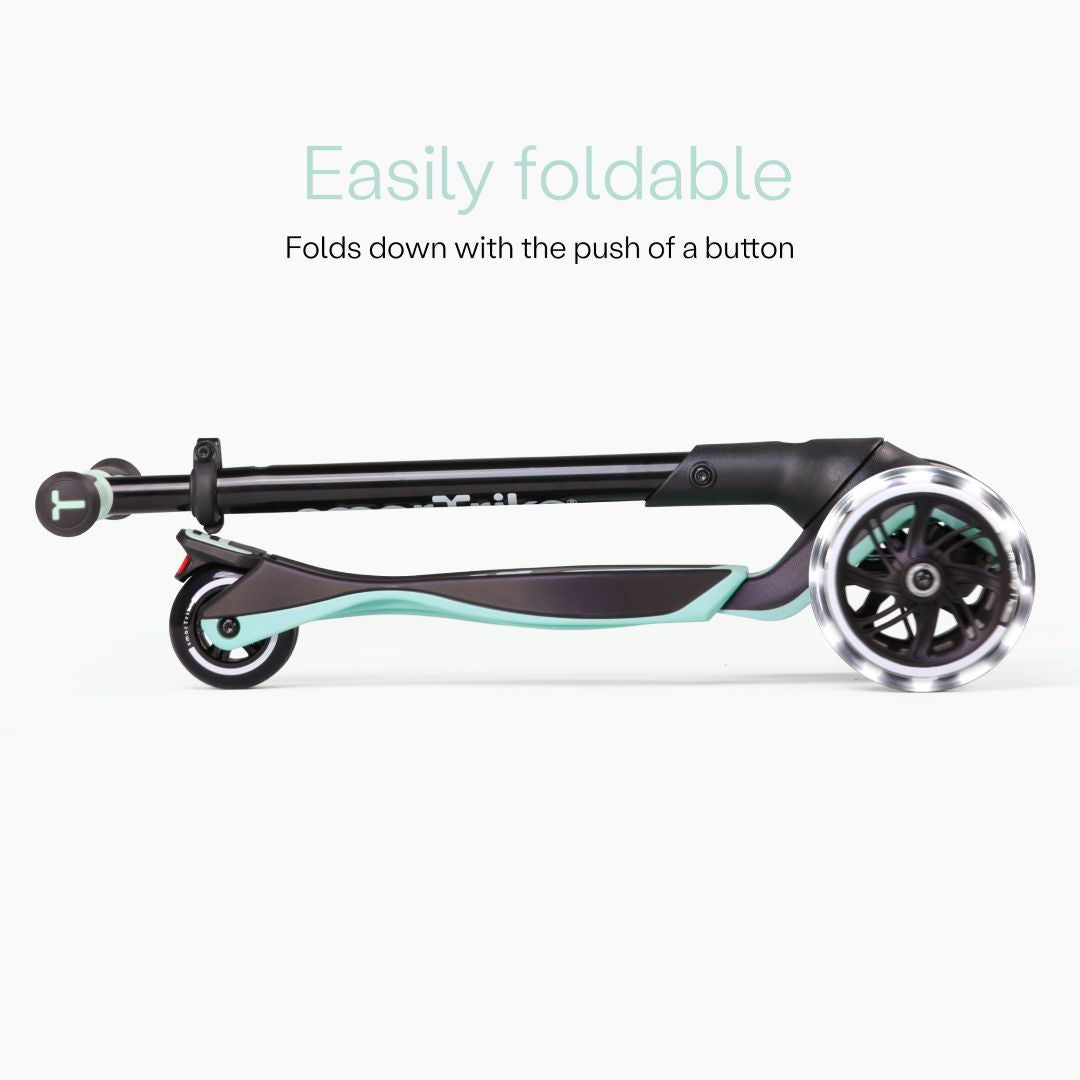 Vista lateral del scooter SmarTrike Xtend Ride-On Verde Agua completamente plegado en formato compacto, con ruedas LED visibles. Texto: "Easily foldable. Folds down with the push of a button." Fondo gris claro.