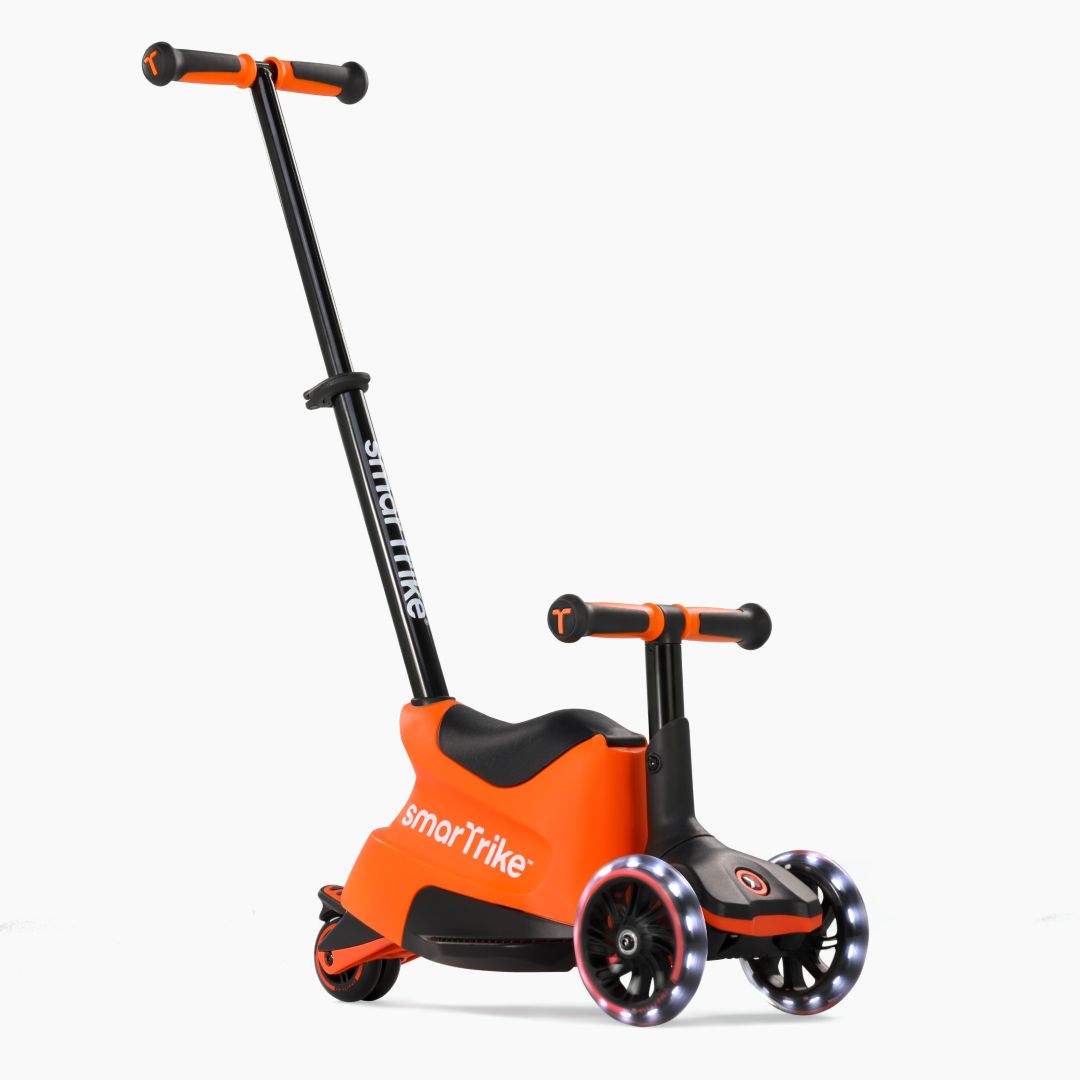 Vista frontal en ángulo del scooter evolutivo SmarTrike Xtend Ride-On Naranjo en modo ride-on, con asiento, manubrio para niño, barra para padres inclinada y tres ruedas con luz LED. Fondo blanco.