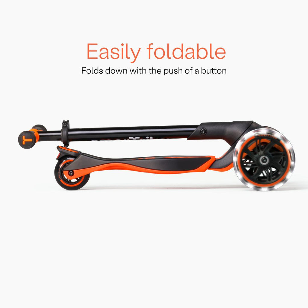 Vista lateral del scooter SmarTrike Xtend Ride-On Naranjo completamente plegado en formato compacto, con ruedas LED visibles. Texto: "Easily foldable. Folds down with the push of a button." Fondo gris claro.