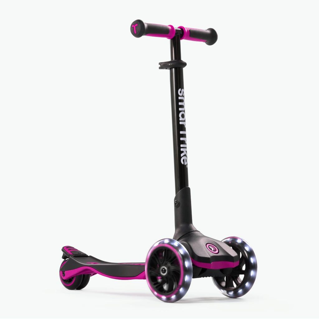 Vista frontal en ángulo del scooter evolutivo SmarTrike Xtend en color rosa, plataforma extensible patentado, tres ruedas XL con luz LED y plataforma antideslizante. Fondo gris claro.