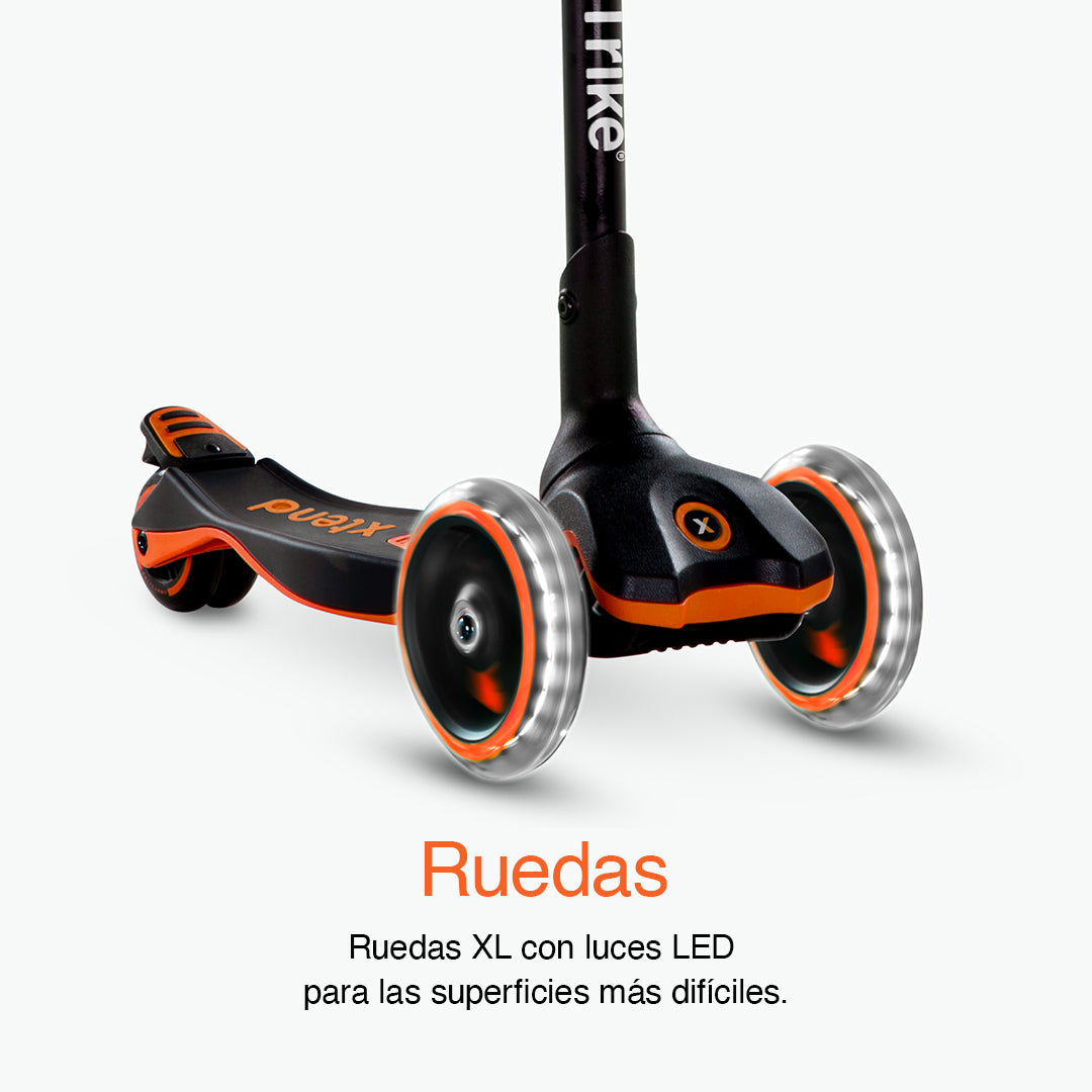 Detalle en primer plano de las tres ruedas XL con luz LED del scooter SmarTrike Xtend naranja , con plataforma y detalles naranjos visibles. Texto: "Ruedas. Ruedas XL con luces LED para las superficies más difíciles." Fondo gris claro.