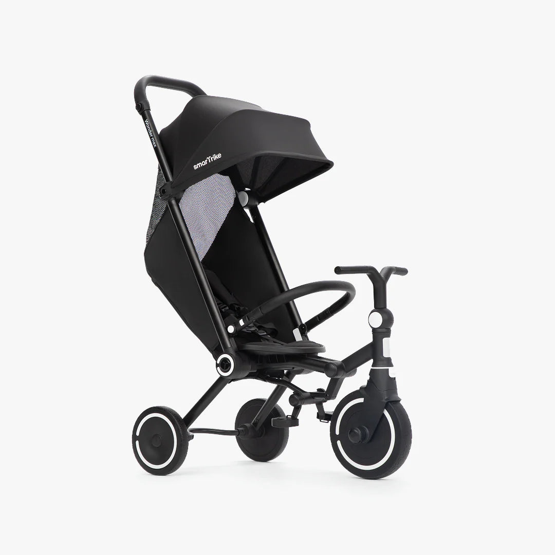 Coche triciclo evolutivo SmarTrike Wonder max color negro, plegable, apto para cabina de avión, uso desde los 6 meses, con dirección Easy-Steer 360° patentado, respaldo reclinable 140 grados, panel de malla transpirable, manubrio para padres, asiento con reposapiés y tres ruedas con aros blancos, fotografiado en ángulo lateral sobre fondo blanco.