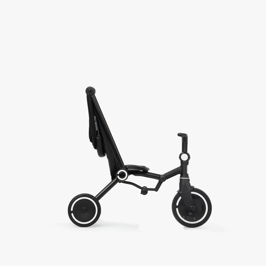 Coche triciclo evolutivo SmarTrike Wonder max color negro, plegable, apto para cabina de avión, uso desde los 6 meses, con dirección Easy-Steer 360° patentado, respaldo reclinable 140 grados, panel de malla transpirable, manubrio para padres, asiento con reposapiés y tres ruedas con aros blancos, fotografiado, en modo triciclo, ángulo lateral sobre fondo blanco.