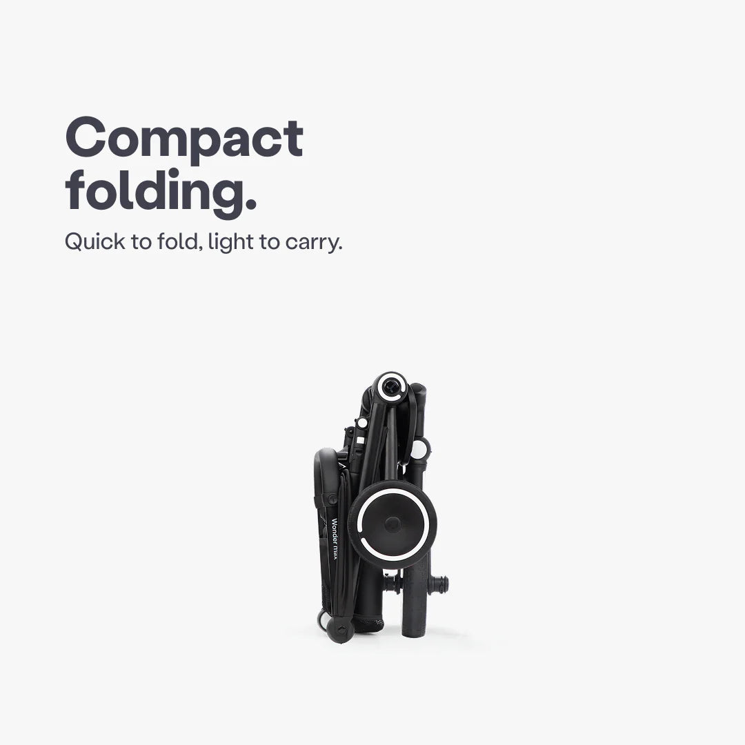 Coche triciclo evolutivo SmarTrike Wonder max color negro, plegable, apto para cabina de avión, uso desde los 6 meses, con dirección Easy-Steer 360° patentado, respaldo reclinable 140 grados, panel de malla transpirable, manubrio para padres, asiento con reposapiés y tres ruedas con aros blancos, fotografiado plegado, ángulo lateral sobre fondo blanco.