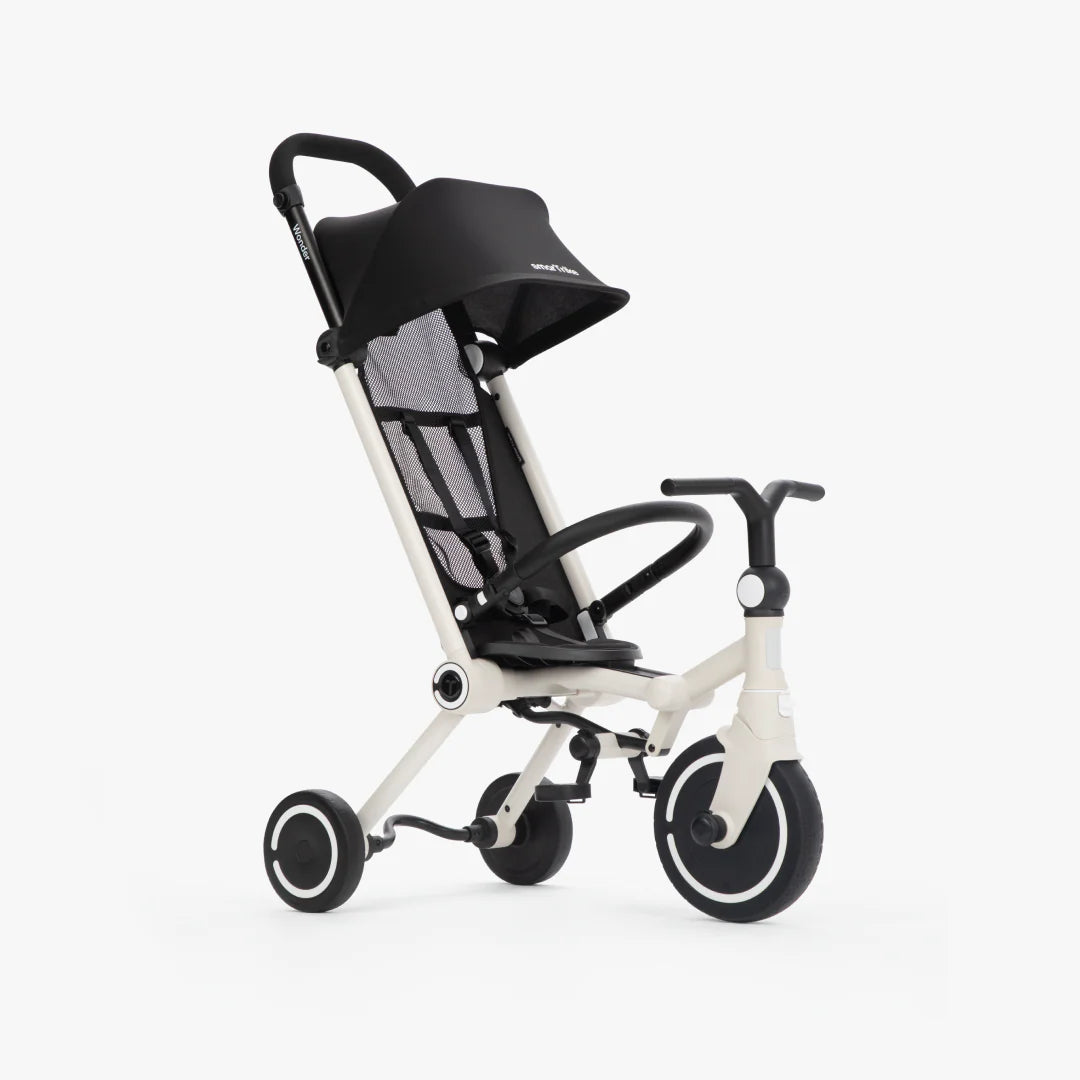 Coche triciclo evolutivo SmarTrike Wonder color blanco, plegable, apto para cabina de avión, uso desde los 9 meses, con dirección Easy-Steer 360° patentado, panel de malla transpirable, manubrio para padres, asiento con reposapiés y tres ruedas con aros blancos, fotografiado en ángulo lateral sobre fondo blanco.