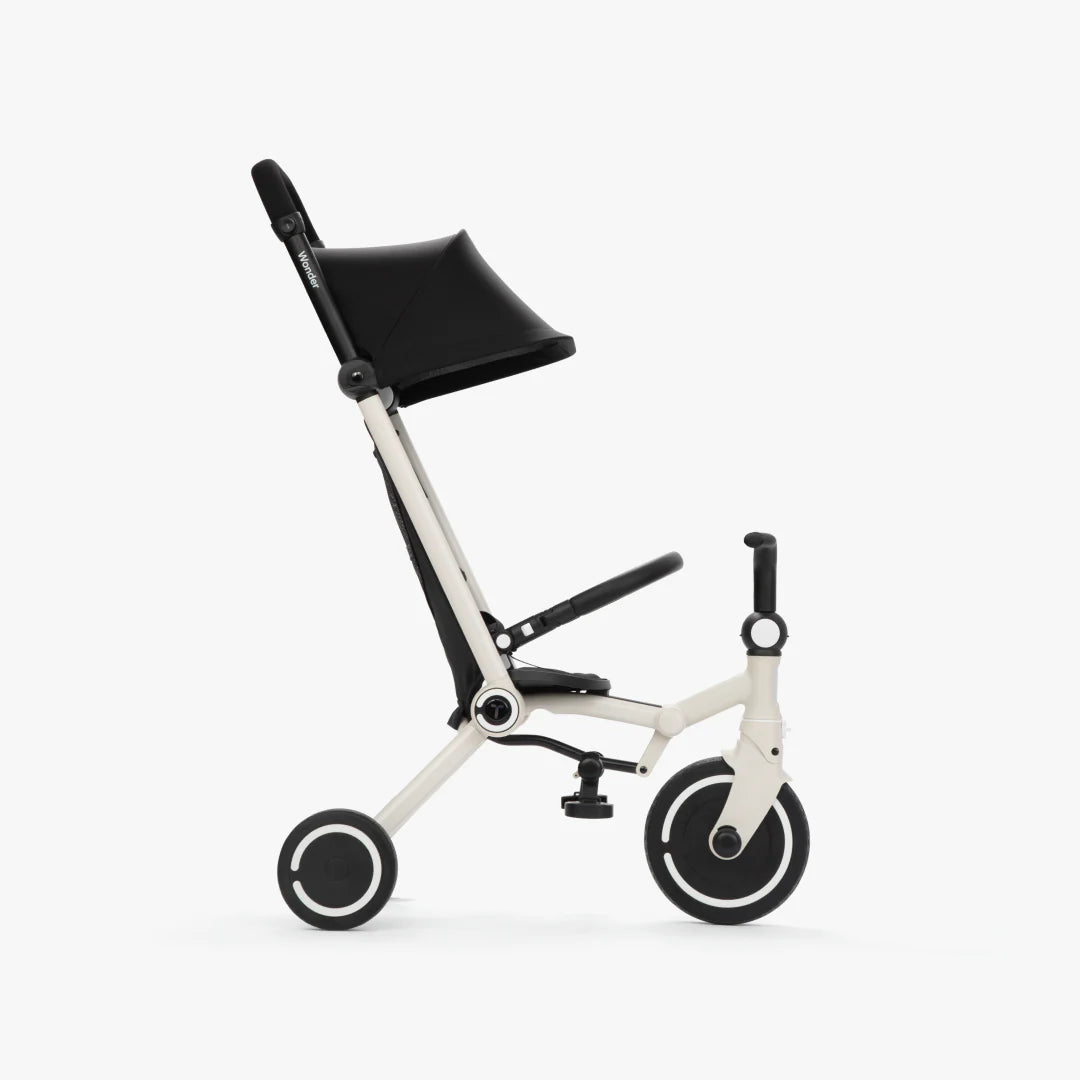 Coche triciclo evolutivo SmarTrike Wonder color blanco, plegable, apto para cabina de avión, uso desde los 9 meses, con dirección Easy-Steer 360° patentado, panel de malla transpirable, manubrio para padres, asiento con reposapiés y tres ruedas con aros blancos, fotografiado, en modo coche, ángulo lateral sobre fondo blanco.