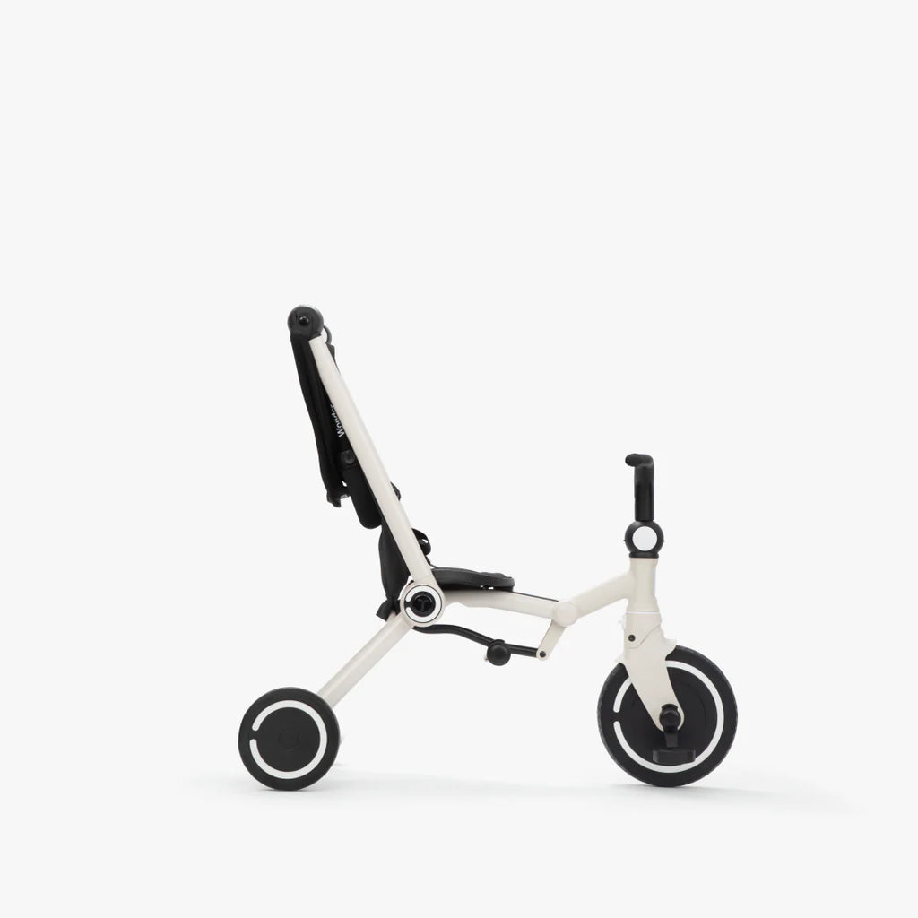 Coche triciclo evolutivo SmarTrike Wonder color blanco, plegable, apto para cabina de avión, uso desde los 9 meses, con dirección Easy-Steer 360° patentado, panel de malla transpirable, manubrio para padres, asiento con reposapiés y tres ruedas con aros blancos, fotografiado, en modo triciclo, ángulo lateral sobre fondo blanco.